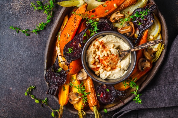 baked-vegetables-with-hummus-in-a-dark-dish-top-view